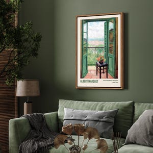May include: A framed poster with a painting of an open balcony door with a view of a city and a small table with a vase of flowers. The poster is titled "ALBERT MARQUET" and has the text "VUE DE LA FENETRE DE L'ATELIER" and "PARIS, 1912".