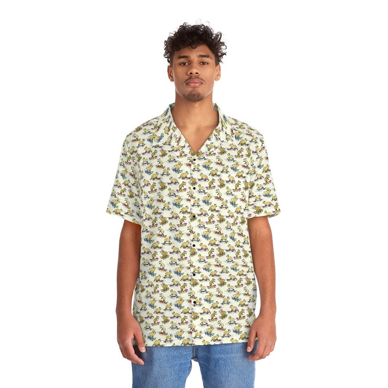 May include: A short-sleeved button-down shirt with a white background and a repeating pattern of brown cartoon dogs riding skateboards. The shirt has a collar and a button-up front.