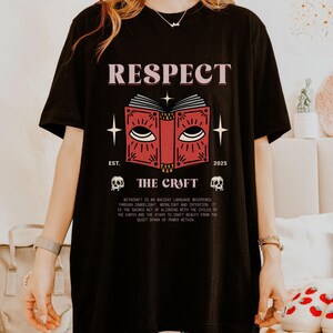 May include: Black t-shirt with the word "RESPECT" above a red book graphic with eyes. The text "THE CRAFT" is below the book, with "EST. 2025" and two skull graphics. The shirt also has a paragraph of text.