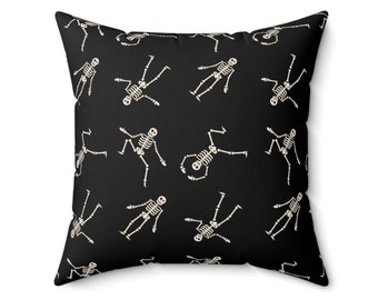 May include: Black throw pillow with a white skeleton pattern. The skeletons are in various poses and are repeated throughout the pillow.