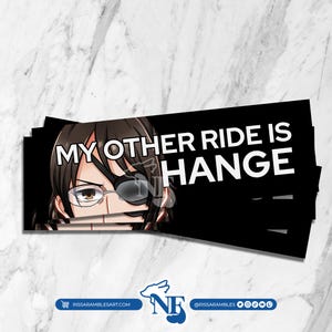 Puede incluir: Una pila de pegatinas negras con el texto "MY OTHER RIDE IS HANGE" en blanco. Las pegatinas presentan una imagen de dibujos animados de una persona con cabello castaño, gafas y un parche en el ojo. Sobre una superficie de mármol blanco.