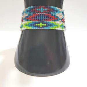 May include: A colorful beaded bracelet with a geometric pattern in shades of blue, green, red, and white.