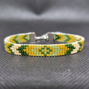 May include: A green, yellow, and white beaded bracelet with a silver clasp.