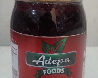 May include: A jar of Adepa Foods Hot Pepper Sauce, labeled "Shito." The jar has a red lid and a red label with green and white text. The label features images of peppers, tomatoes, and onions.