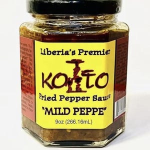Op de afbeelding: Een pot Liberia's Premier KONTO Fried Pepper Sauce, met het label "MILD PEPPE". De heldere glazen pot heeft een zwarte deksel en een geel etiket met bruine tekst. De pot bevat 266,16 ml saus.