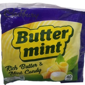 Puede incluir: Un paquete de caramelos Cadbury Butter Mint. El envase es principalmente amarillo y verde, con las palabras "Butter mint" en letras verdes grandes. También es visible el texto "Rich Butter & Mint Candy". Contiene 40 unidades.