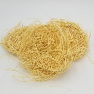 May include: A pile of natural, light yellow, shredded sisal fiber. The sisal is a natural material used for crafting and decorating.