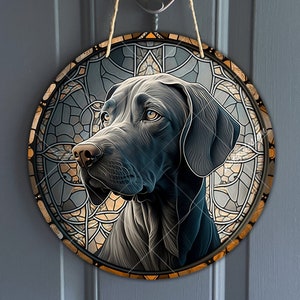 Puede incluir: Un colgador de puerta redondo de estilo vitral con un perro Braco Alemán de Pelo Corto negro con la nariz marrón. La cabeza del perro está centrada en el diseño circular, con un patrón de vitral detrás.