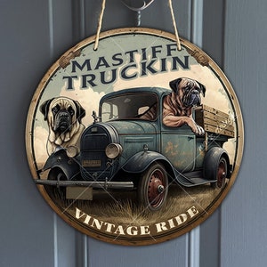 May include: A round wooden sign featuring a vintage truck and two Mastiff dogs. The sign reads "Mastiff Truckin' Vintage Ride".