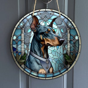 Può includere: Un'appendice murale rotonda in stile vetrata con un cane Doberman nero e marrone con un collare blu e argento. Lo sfondo è un mosaico di vetro blu, verde e argento.