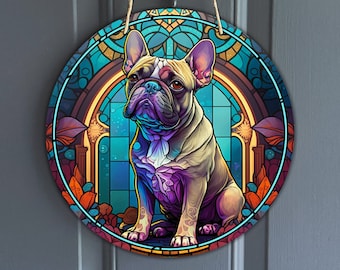Puede incluir: Un diseño redondo de vitral colorido con un Bulldog Francés sentado en un arco decorativo. El perro está representado en un esquema de colores vibrantes morado, azul y amarillo.