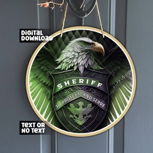 May include: A round wooden sign with a green, black, and gold design. A green eagle with a gold beak and talons is centered on the sign. The eagle is holding a shield with the words "SHERIFF" in gold letters, "TO PROTECT" in black letters, and "AND SERVE" in black letters. The sign has a rope hanger.