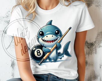 May include: A white t-shirt with a cartoon shark holding a pool cue and a black and blue eight ball.