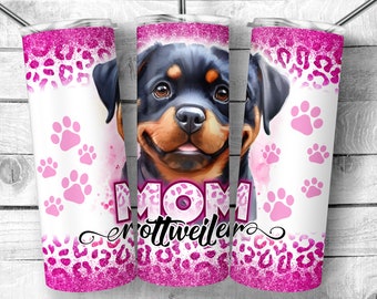 Op de afbeelding: Een roze en witte tumbler met een zwart en bruin Rottweiler-puppy gezicht, poot afdrukken en de tekst "MOM Rottweiler".