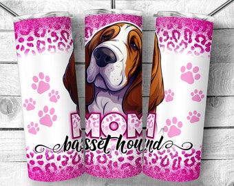 Op de afbeelding: Een roze en witte tumbler met een roze luipaardprint. De tumbler heeft een cartoon afbeelding van een basset hound met de tekst "MOM basset hound".
