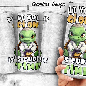 Puede incluir: Un vaso blanco con una tortuga de dibujos animados que lleva un kimono de karate y el texto "Put your gi on it's cuddle time".