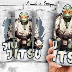 Op de afbeelding: Een witte tumbler met een groen en oranje cartoonfiguur dat een wit karatepak en een zwarte band draagt. De tekst "Jiu Jitsu" is op de tumbler gedrukt.