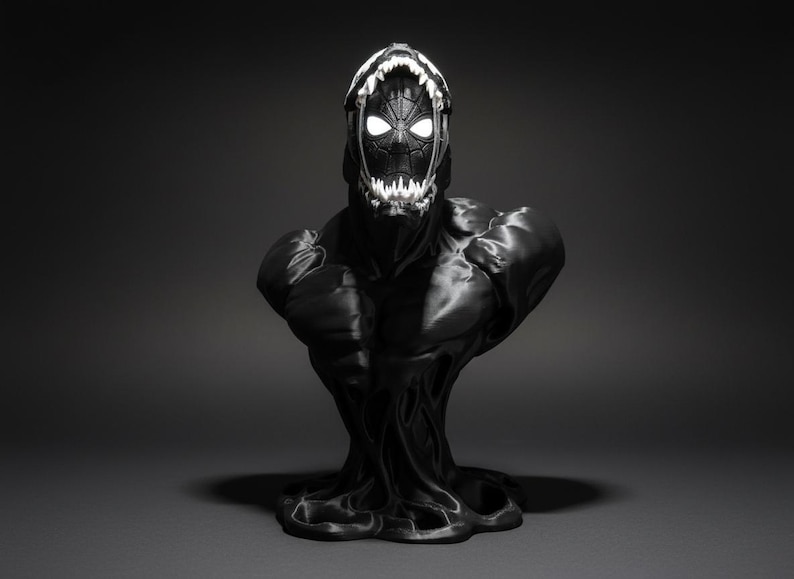 Puede incluir: Busto negro inspirado en Venom. La escultura presenta una cabeza detallada con una boca abierta y dientes blancos brillantes. Los ojos tambi&eacute;n brillan en blanco. El pecho y los hombros son musculosos, y la base tiene un dise&ntilde;o org&aacute;nico y fluido.