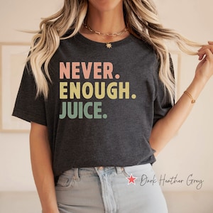 May include: A dark heather grey t-shirt with the text "NEVER. ENOUGH. JUICE." printed in colorful letters.