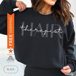 May include: Black sweatshirt with the text "hair therapist" in white and gray lettering.