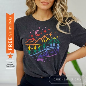 May include: Dark heather grey t-shirt with a rainbow mountain scene and a campfire graphic. The text "DARK HEATHER GREY" is printed on a white button below the image.