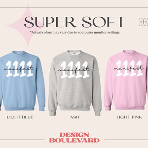 May include: Three sweatshirts with the text "manifest 1111" in white on a light blue, ash grey, and light pink background. The sweatshirts are all crew neck and have long sleeves.