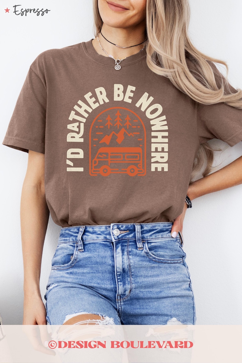 May include: A brown t-shirt with the text "I'D RATHER BE NOWHERE" in cream, featuring an orange camper van graphic. The shirt is worn with blue jeans. The word "Espresso" is in the top left corner.