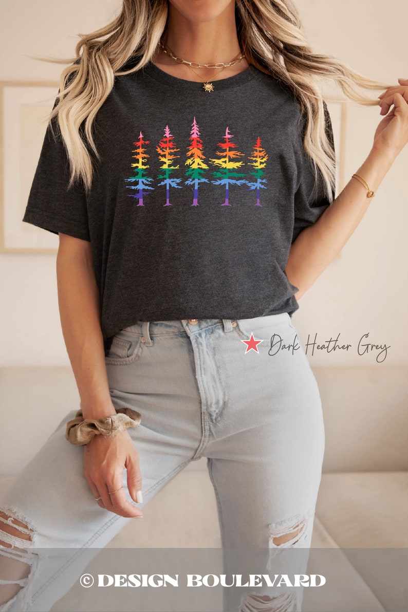 Op de afbeelding: Een donkergrijs gem&ecirc;leerd T-shirt met korte mouwen en een grafische print van vijf dennenbomen op een rij. Elke boom is voorzien van horizontale strepen in een regenboogkleurverloop. Het T-shirt heeft een ronde hals en een relaxte pasvorm.