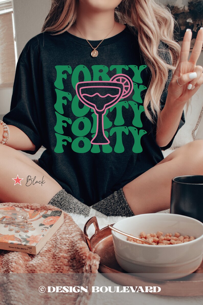 May include: A black t-shirt featuring a graphic print with the word FORTY repeated in a wavy green font. Centered in the design is a pink outline of a margarita glass with a lime wedge garnish. The text is arranged in four rows behind the glass.