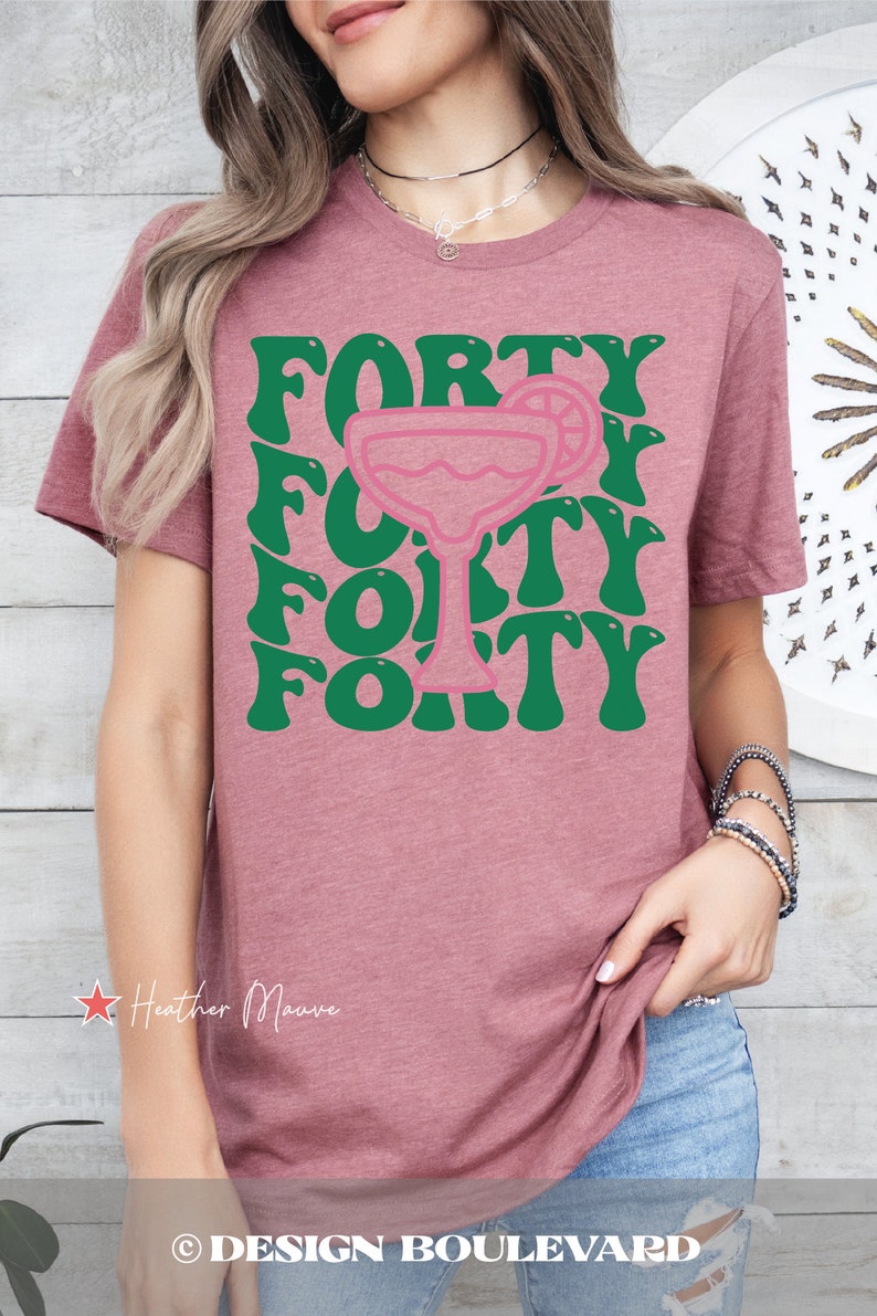 May include: A heather mauve short-sleeve t-shirt featuring a graphic print with the word FORTY repeated in a wavy green font, centered around a pink outline of a margarita glass with a lime slice garnish on the rim of the glass.