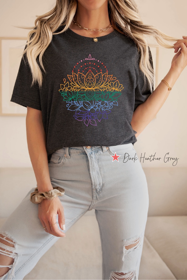 K&ouml;nnte beinhalten: Ein dunkel-melierter grauer T-Shirt mit einem Regenbogen-Mandala-Design. Das Mandala zeigt eine Lotusblume mit filigranen Details und ist von Bl&auml;ttern und Spiralen umgeben.