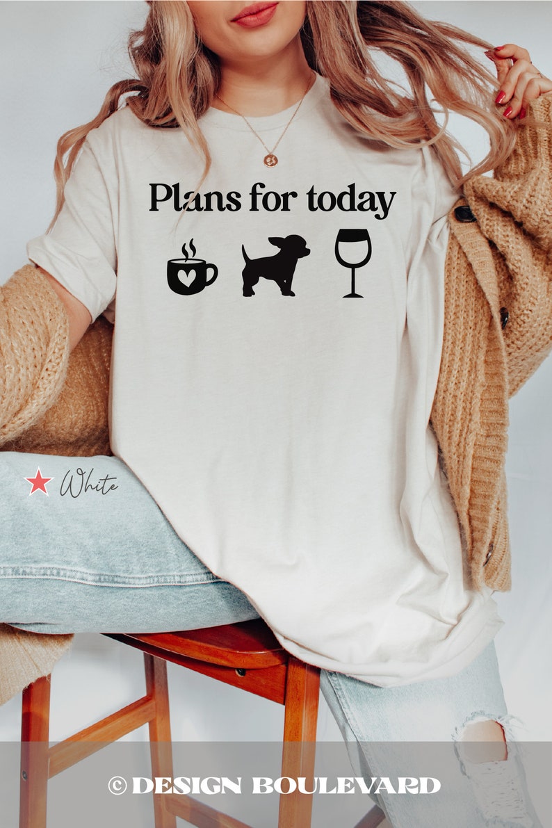 May include: A white t-shirt featuring the black text "Plans for today" above three black icons: a coffee mug with a heart, a small dog silhouette, and a wine glass. The shirt is worn with a tan cardigan and light blue denim jeans.