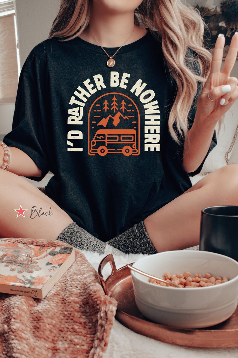 May include: Black t-shirt with a graphic of a vintage van driving through a mountain landscape with the text "I'd rather be nowhere".