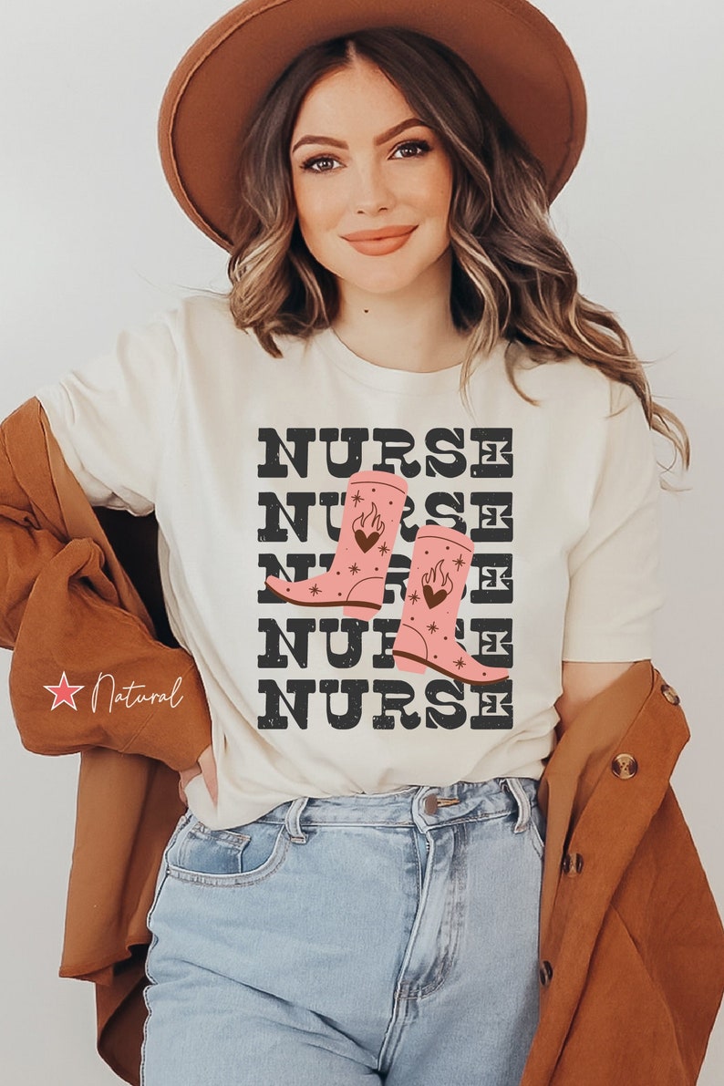 May include: A white t-shirt with the word "NURSE" repeated five times in black text. The word "NURSE" is stacked vertically with a pair of pink cowboy boots with flames and stars on them between the second and third "NURSE".
