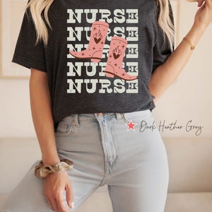 May include: Dark heather grey t-shirt with the text "NURSE" repeated five times and a graphic of pink cowboy boots with flames and hearts.