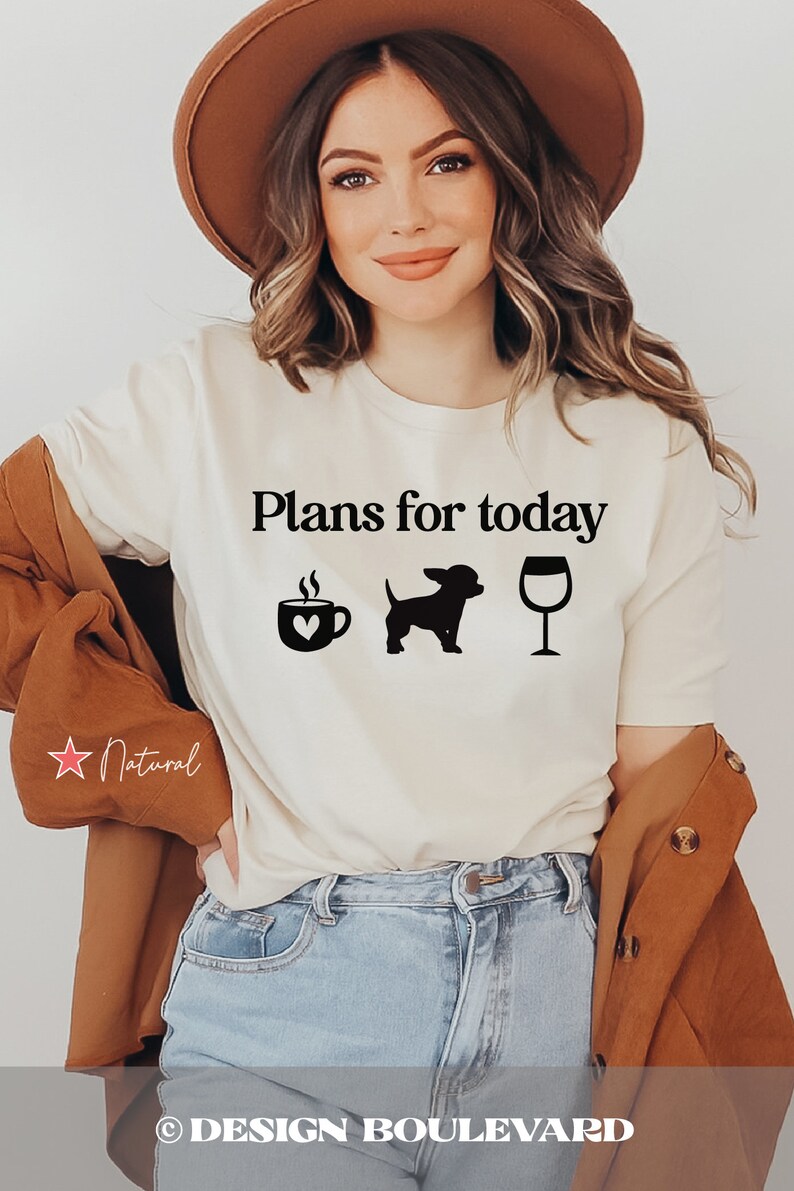 May include: A cream-colored short-sleeve t-shirt featuring the black text "Plans for today" above three black icons: a coffee mug with a heart, a small dog silhouette, and a wine glass. The shirt is worn with a brown hat and a brown jacket.
