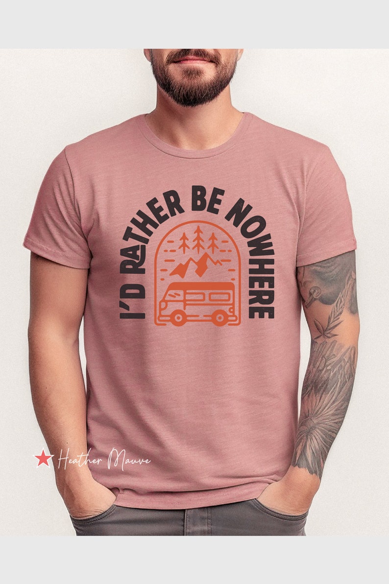 May include: A heather mauve t-shirt with a graphic print of a camper van driving through a mountain landscape with trees. The text "I'd rather be nowhere" is printed in a black semi-circle around the graphic.