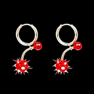 May include: A pair of silver hoop earrings with red and white polka dot ball charms. The charms are attached to the hoops with a silver bar.