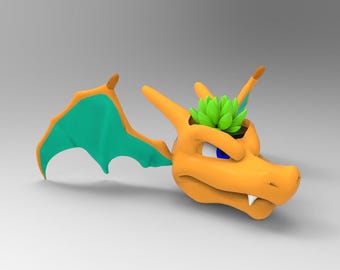 May include: Orange and green ceramic planter shaped like a dragon's head with a small green plant growing out of the top.