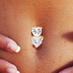 May include: A gold belly button ring with two clear heart-shaped stones.