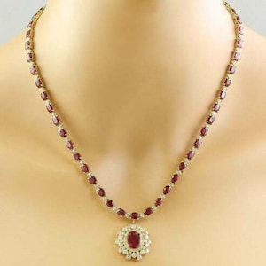 May include: A gold necklace with a ruby pendant. The necklace is made of small oval-shaped rubies and diamonds. The pendant is a large oval-shaped ruby surrounded by diamonds.
