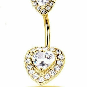 May include: Gold belly button ring with two heart-shaped charms, each with a clear crystal in the center and a halo of smaller crystals.