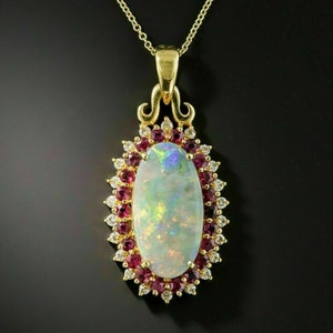 May include: A gold pendant necklace featuring a large oval opal set within a halo of smaller diamonds and rubies.