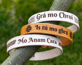 May include: Three leather bracelets with Celtic knot designs and Irish phrases: "Grá mo Chroi", "Is tú mo ghrá", and "Mo Anam Cara".