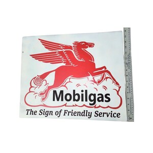 May include: Vintage Mobilgas sign with a red Pegasus emblem and the words "Mobilgas" and "The Sign of Friendly Service" in black. The sign is white with a red Pegasus design.