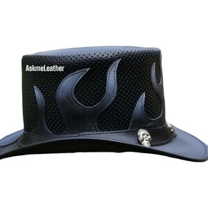 Pu&ograve; includere: Un cappello da cowboy in pelle nera con un design a fiamma e dettagli a forma di teschio. Il cappello ha una parte superiore perforata e un'ampia tesa.
