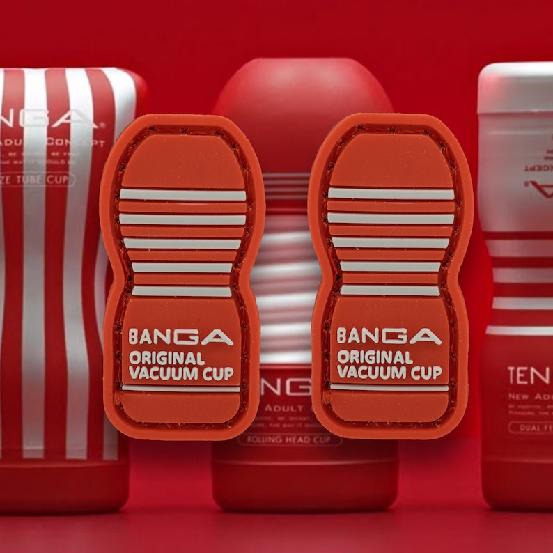 Pu&ograve; includere: Due ventose in silicone a strisce rosse e bianche con la scritta "BANGA ORIGINAL VACUUM CUP" stampata su di esse. Le ventose sono su una superficie rossa.
