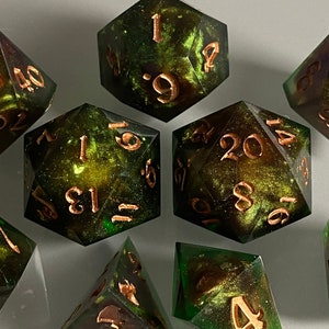 May include: A set of eight green and gold dice with copper-colored numbers. The dice are made of resin and have a speckled, galaxy-like appearance.
