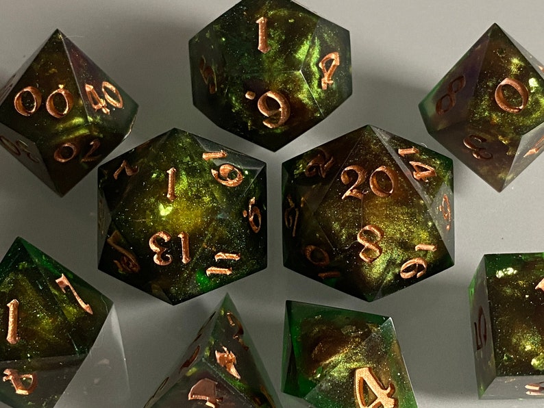 May include: A set of eight green and gold dice with copper-colored numbers. The dice are made of resin and have a speckled, galaxy-like appearance.