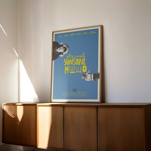 Puede incluir: Un póster azul con un marco blanco que presenta el título de la película "Eternal Sunshine of the Spotless Mind" en texto amarillo. El póster también presenta los nombres de los actores de la película, incluyendo Kate Winslet, Jim Carrey, Kirsten Dunst, Mark Ruffalo, Elijah Wood y Tom Wilkinson.